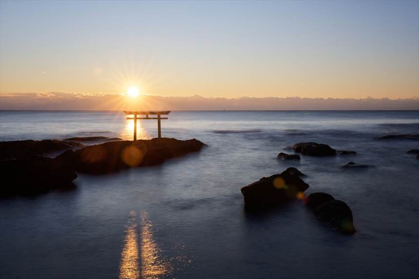 神磯の鳥居の左後ろから昇る朝日と光の筋